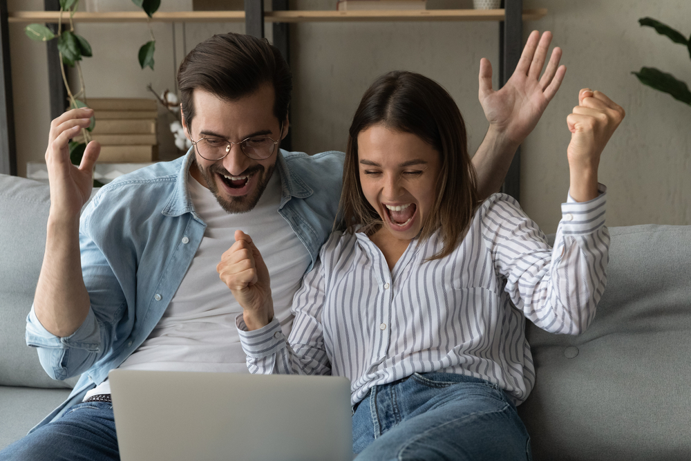 Euphoric,Couple,Cheerful,Male,Female,Read,Unbelievable,News,On,Laptop Importancia Sistema de Roll Over nos Bonus de Boas vindas